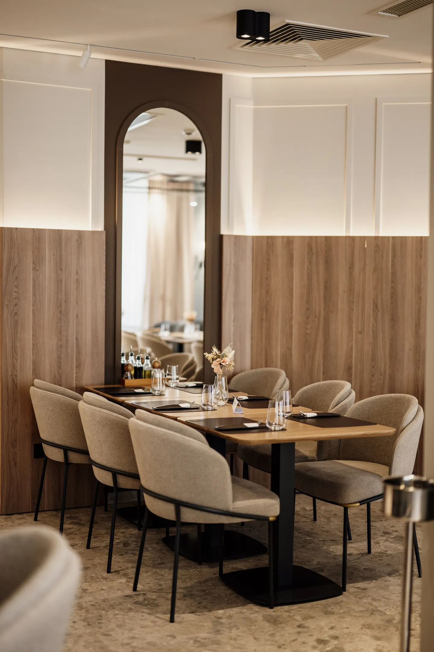A long table set for dinner in a warmly lit restaurant with wood-panelled walls